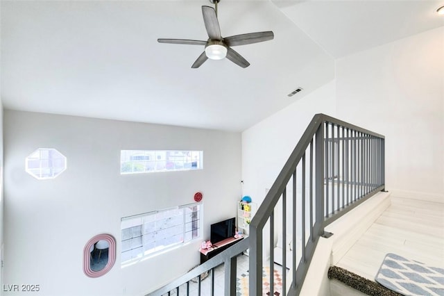 stairway with hardwood / wood-style flooring and ceiling fan