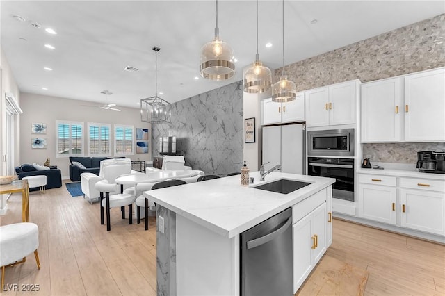 2503 Cracked Stone St, Henderson, NV 89044 - kitchen with stainless steel appliances, an accent wall, a sink, open floor plan, and decorative light fixtures