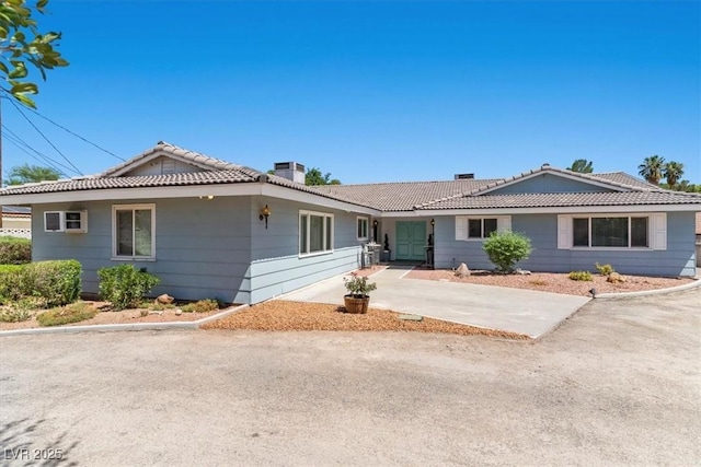 single story home featuring driveway, a chimney, and a tile roof