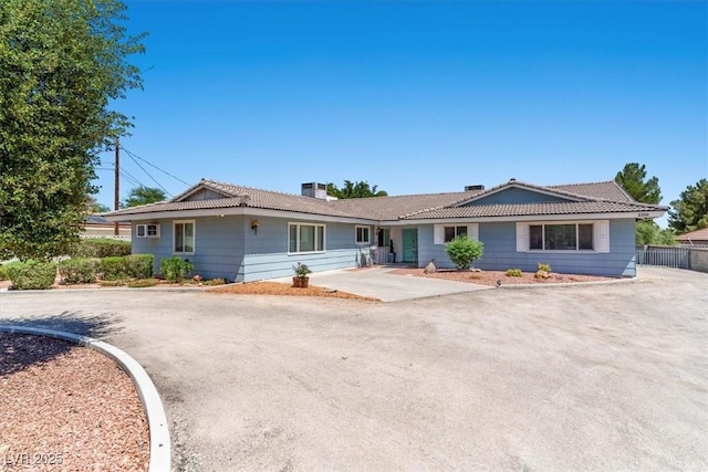 ranch-style house with fence and a tiled roof