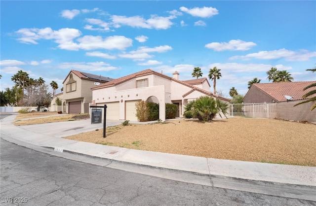 mediterranean / spanish-style house featuring an attached garage, fence, a tile roof, stucco siding, and driveway