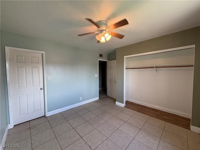 unfurnished bedroom with light tile patterned flooring, ceiling fan, and a closet