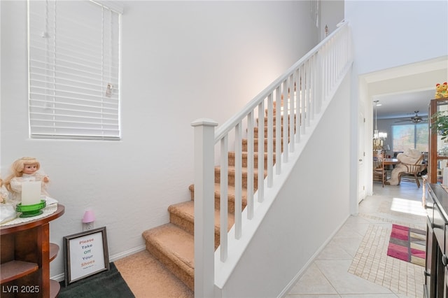 stairway featuring ceiling fan and tile patterned flooring