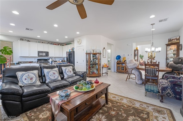 tiled living room with ceiling fan with notable chandelier