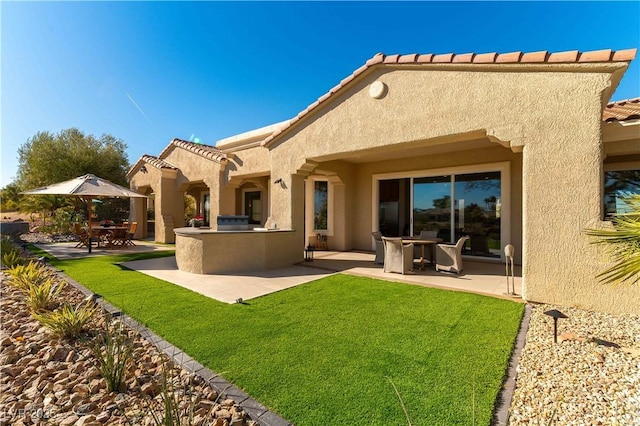 4796 Riva De Romanza St, Las Vegas, NV 89135 - rear view of property featuring a patio, stucco siding, a yard, and an outdoor kitchen