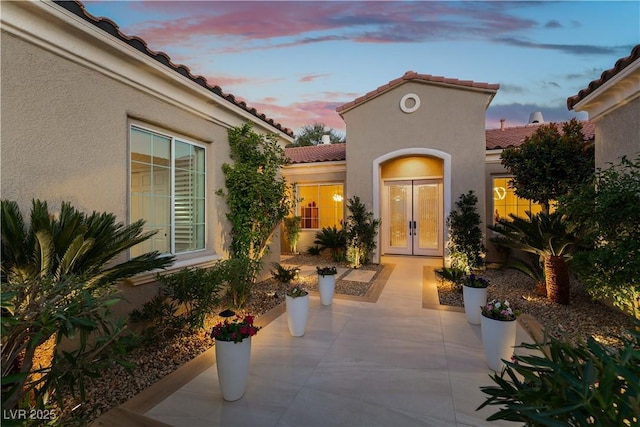 exterior entry at dusk featuring a patio and french doors