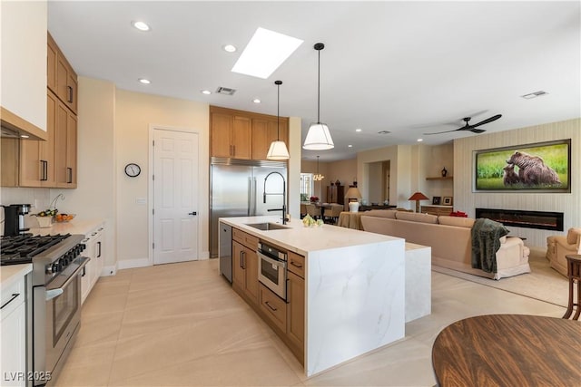 4796 Riva De Romanza St, Las Vegas, NV 89135 - kitchen featuring premium appliances, light countertops, a center island with sink, hanging light fixtures, and light tile patterned floors
