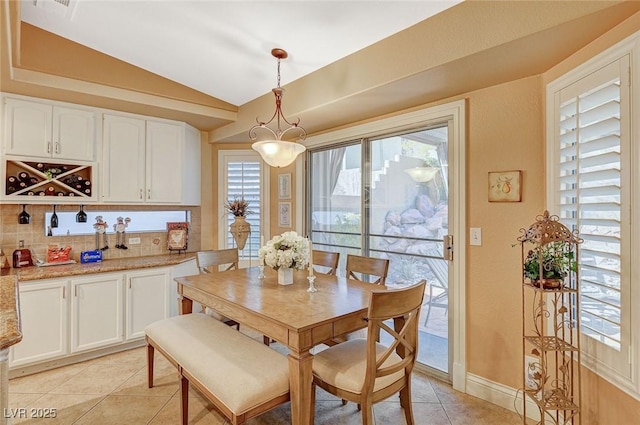 dining room featuring light tile patterned flooring and vaulted ceiling