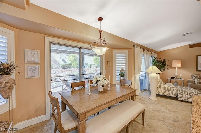 dining space with light tile patterned floors and vaulted ceiling