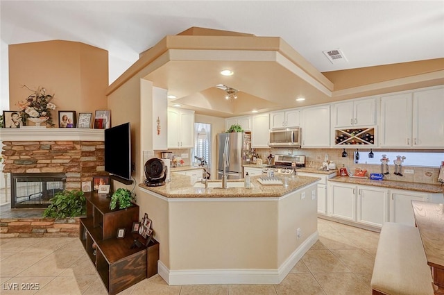 kitchen with white cabinetry, a tray ceiling, appliances with stainless steel finishes, and light stone countertops