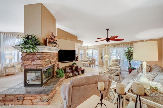 living room featuring a fireplace, ceiling fan, and light tile patterned flooring