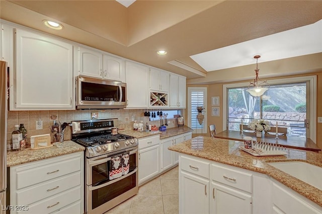 kitchen featuring decorative light fixtures, tasteful backsplash, stainless steel appliances, and white cabinets