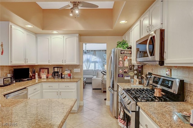 kitchen featuring white cabinets, light tile patterned floors, stainless steel appliances, and decorative backsplash