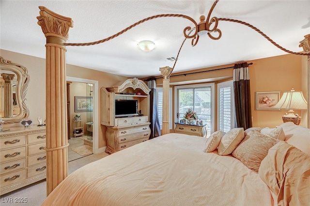 bedroom featuring decorative columns, light carpet, and ensuite bathroom