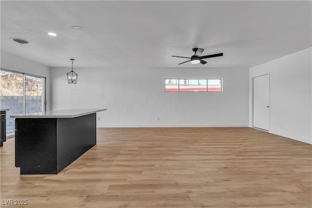 interior space featuring visible vents, light wood-style flooring, baseboards, and ceiling fan with notable chandelier