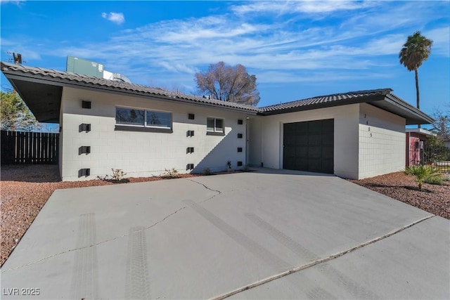 single story home featuring an attached garage, driveway, fence, and concrete block siding