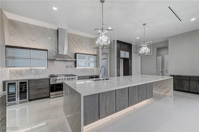 kitchen featuring sink, double oven range, a spacious island, light stone counters, and wall chimney exhaust hood