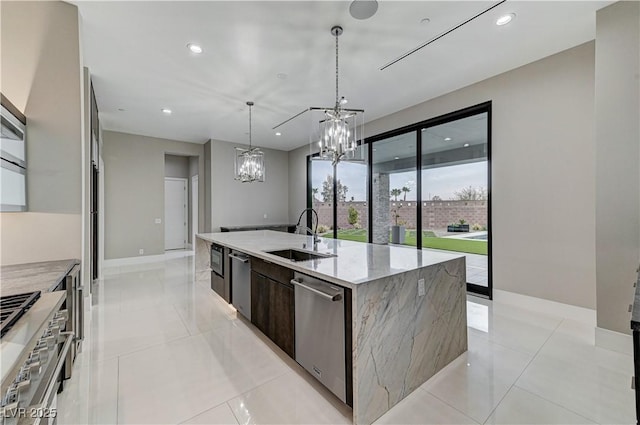 kitchen featuring sink, dark brown cabinets, stainless steel appliances, light stone countertops, and a center island with sink