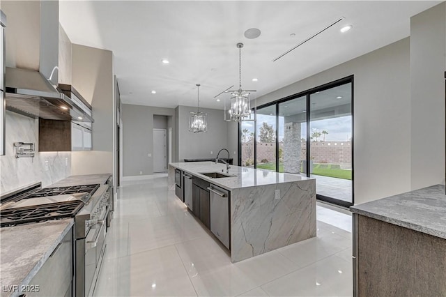 kitchen featuring a spacious island, sink, light stone counters, decorative light fixtures, and stainless steel appliances