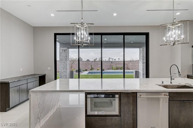 kitchen featuring an inviting chandelier, dark brown cabinetry, sink, and hanging light fixtures