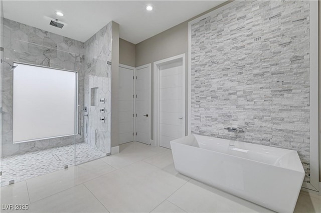 bathroom featuring plus walk in shower, tile patterned flooring, and tile walls