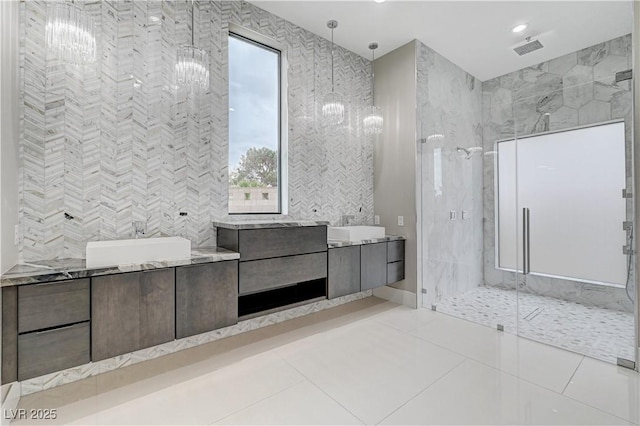 bathroom with tile patterned flooring, vanity, tile walls, and a tile shower