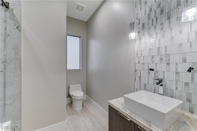 bathroom featuring vanity, toilet, and tile walls