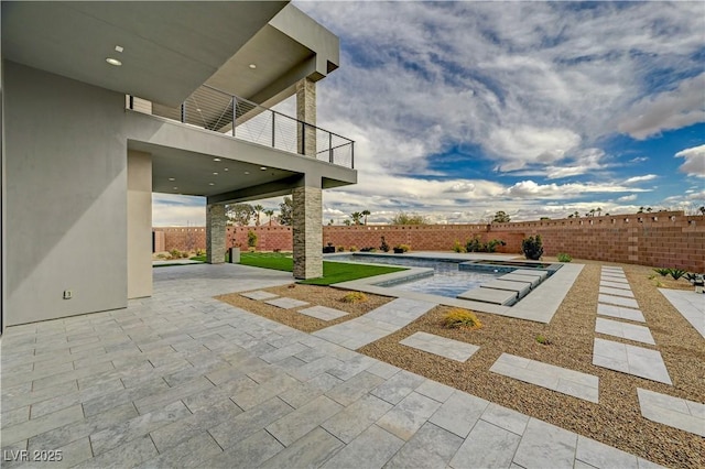 view of patio featuring a fenced in pool and a balcony