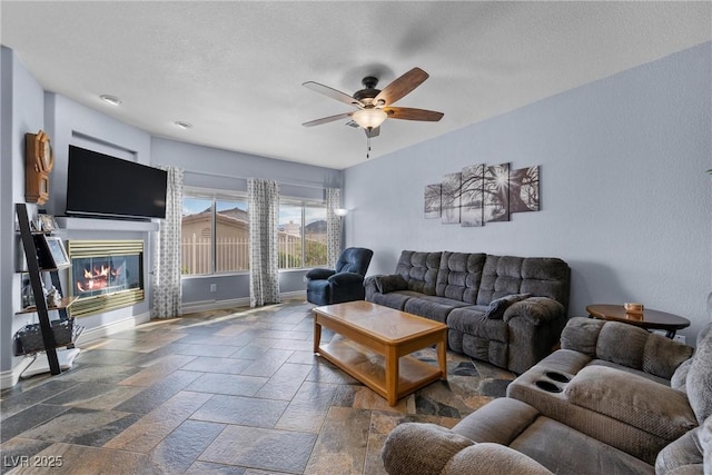 262 Big Horn Dr, Boulder City, NV 89005 - living area with a ceiling fan, a glass covered fireplace, stone tile flooring, and a textured ceiling