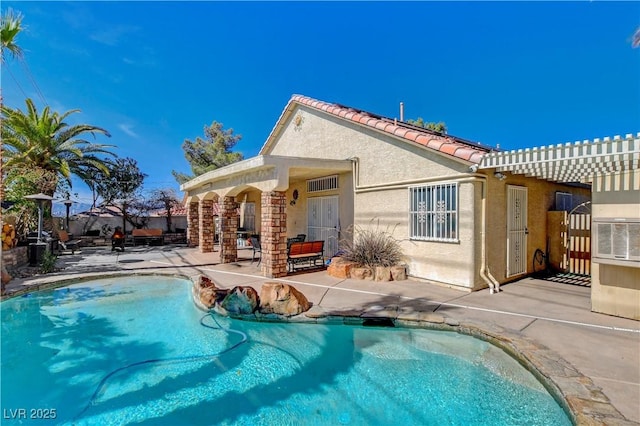 rear view of property with an outdoor pool, a pergola, a patio area, and stucco siding