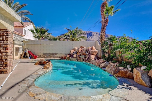 view of pool with a mountain view, a fenced backyard, a fenced in pool, and a patio area