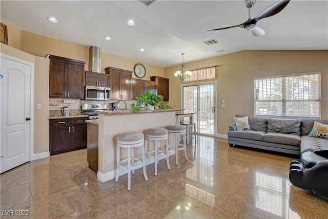kitchen with baseboards, open floor plan, visible vents, a kitchen bar, and stainless steel appliances