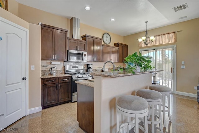 kitchen featuring a breakfast bar area, appliances with stainless steel finishes, baseboards, and visible vents