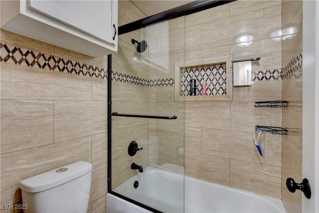 bathroom featuring toilet and bath / shower combo with glass door