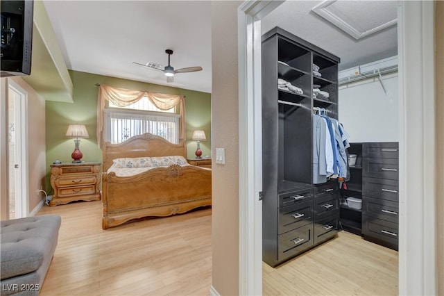 bedroom featuring light wood-style floors, a closet, attic access, and ceiling fan