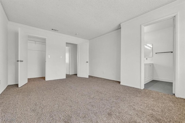 unfurnished bedroom with ensuite bath, ornamental molding, carpet, and a textured ceiling