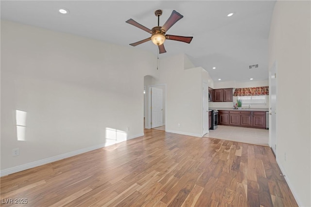 unfurnished living room featuring light wood-type flooring, sink, and ceiling fan