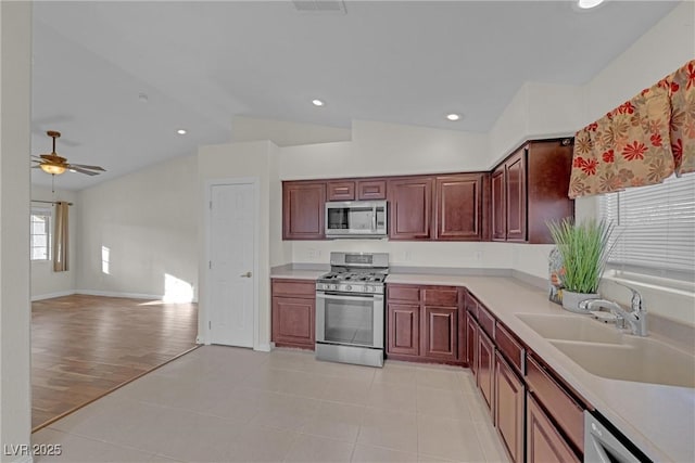 kitchen featuring lofted ceiling, stainless steel appliances, sink, ceiling fan, and light tile patterned floors