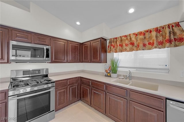 kitchen featuring light tile patterned flooring, lofted ceiling, stainless steel appliances, and sink