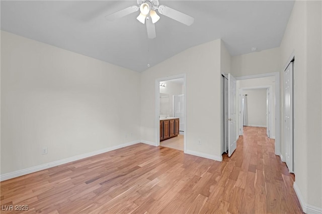 unfurnished bedroom with ceiling fan, light hardwood / wood-style floors, vaulted ceiling, and ensuite bath