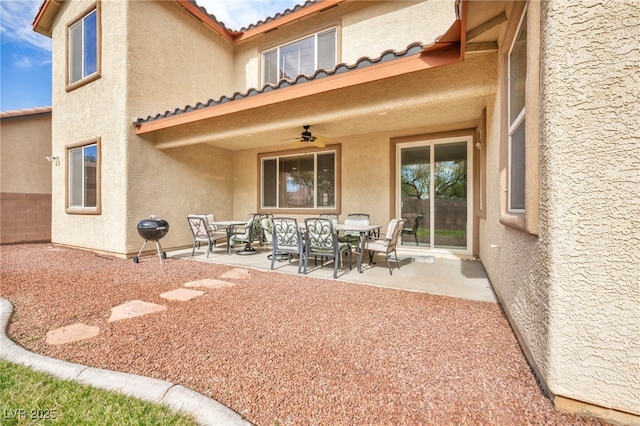 rear view of house featuring a tiled roof, stucco siding, outdoor dining area, and a patio area