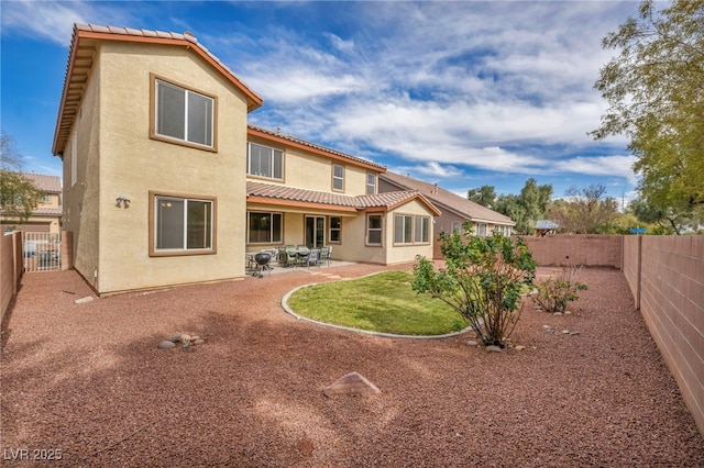 back of house with a tiled roof, a patio area, a fenced backyard, and stucco siding