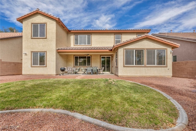 back of property featuring fence, a tile roof, stucco siding, a yard, and a patio area