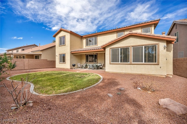 back of house with a tiled roof, a patio area, a fenced backyard, and stucco siding