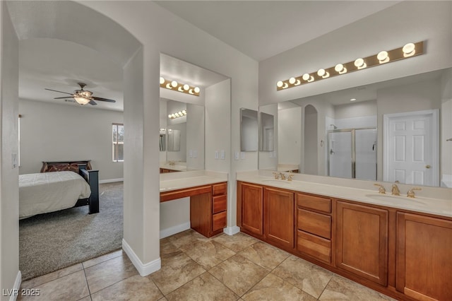 bathroom featuring a shower stall, connected bathroom, double vanity, and a sink