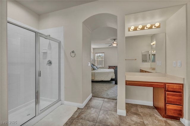 ensuite bathroom featuring a shower stall, a ceiling fan, baseboards, and connected bathroom