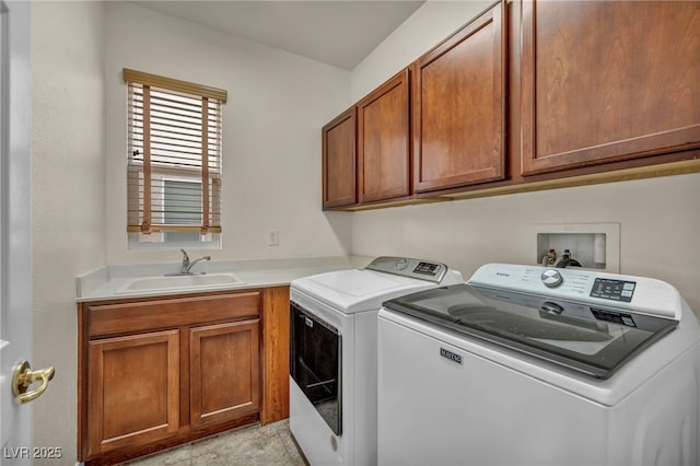 clothes washing area featuring washer and clothes dryer, cabinet space, and a sink