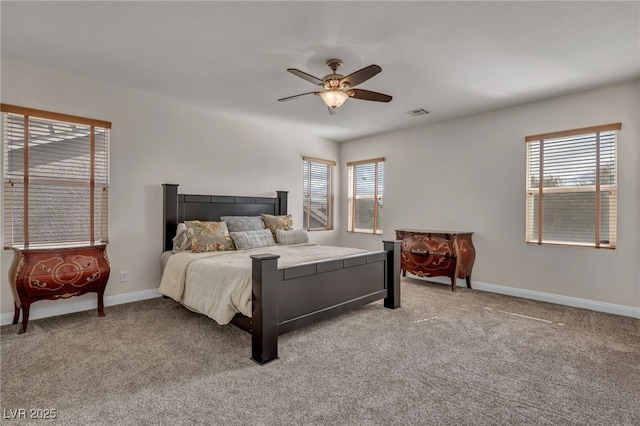 carpeted bedroom with visible vents, multiple windows, baseboards, and ceiling fan