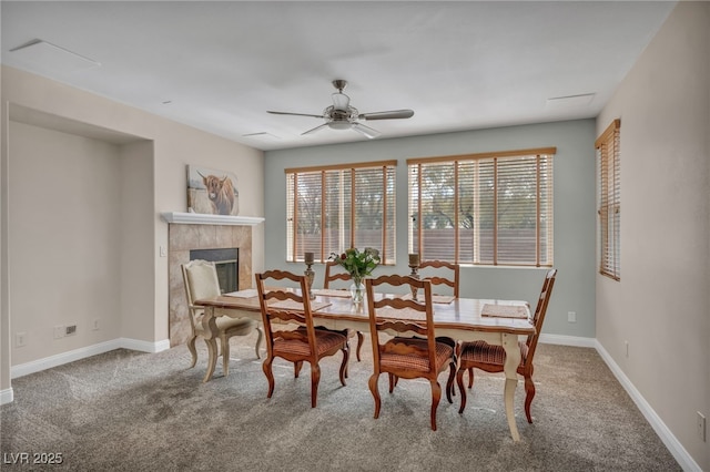 dining area with a tiled fireplace, a ceiling fan, baseboards, and carpet floors