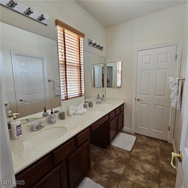 full bath with double vanity, baseboards, and a sink